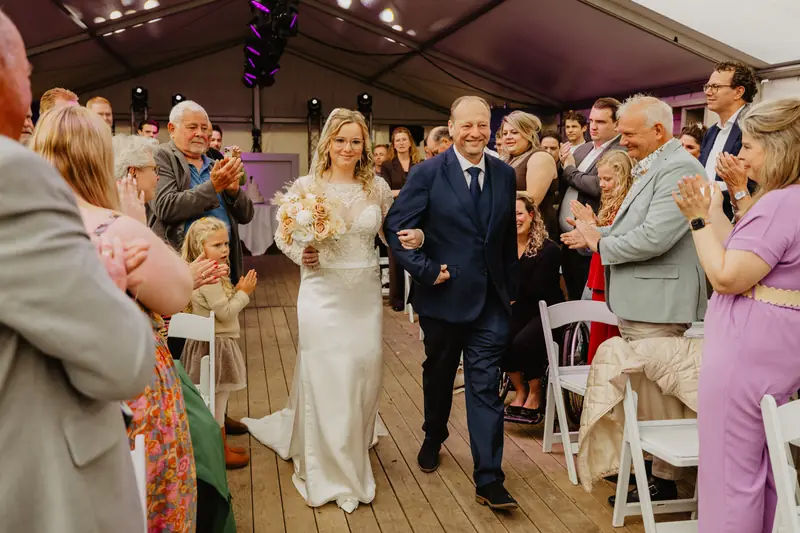 Bruidspaar loopt na de ceremonie tussen juichende gasten