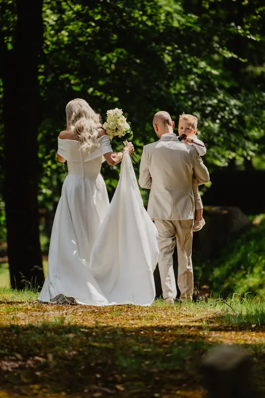 Bruid loopt met haar vader en zoontje naar de ceremonie