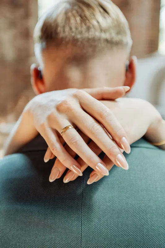 Hand met trouwring op de schouder van de bruidegom