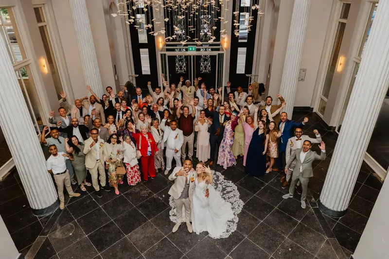 Grote groepsfoto van bovenaf in een zaal met zuilen