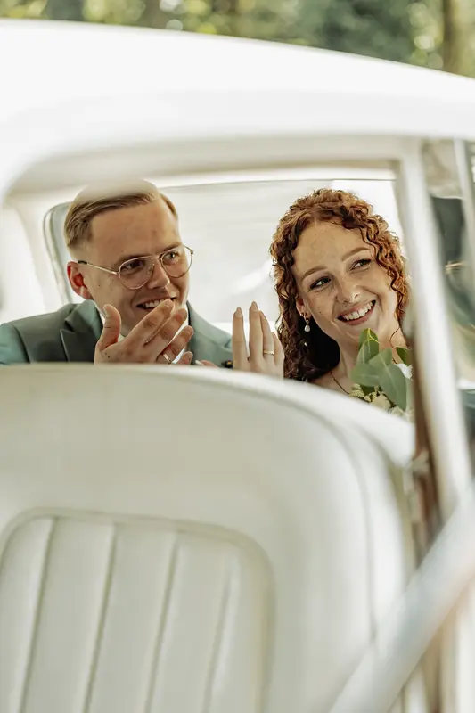 Bruidspaar lacht samen in een oldtimer