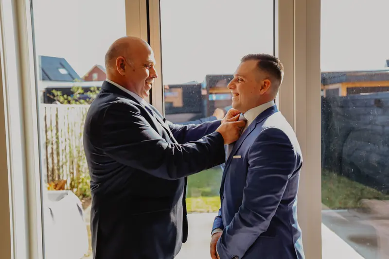 Vader helpt de bruidegom met zijn das