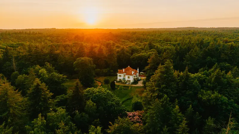 Landhuis in het bos bij zonsondergang, vanuit de lucht