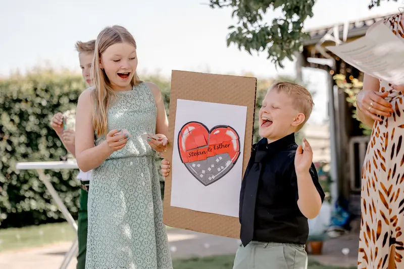 Kinderen met een hartjesbord voor het bruidspaar