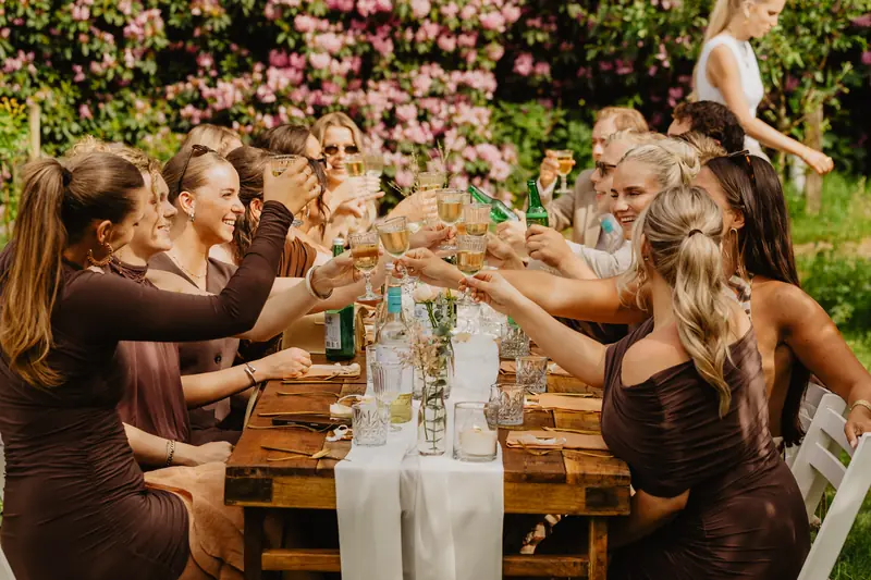 Vriendinnen proosten aan een lange tafel in de tuin